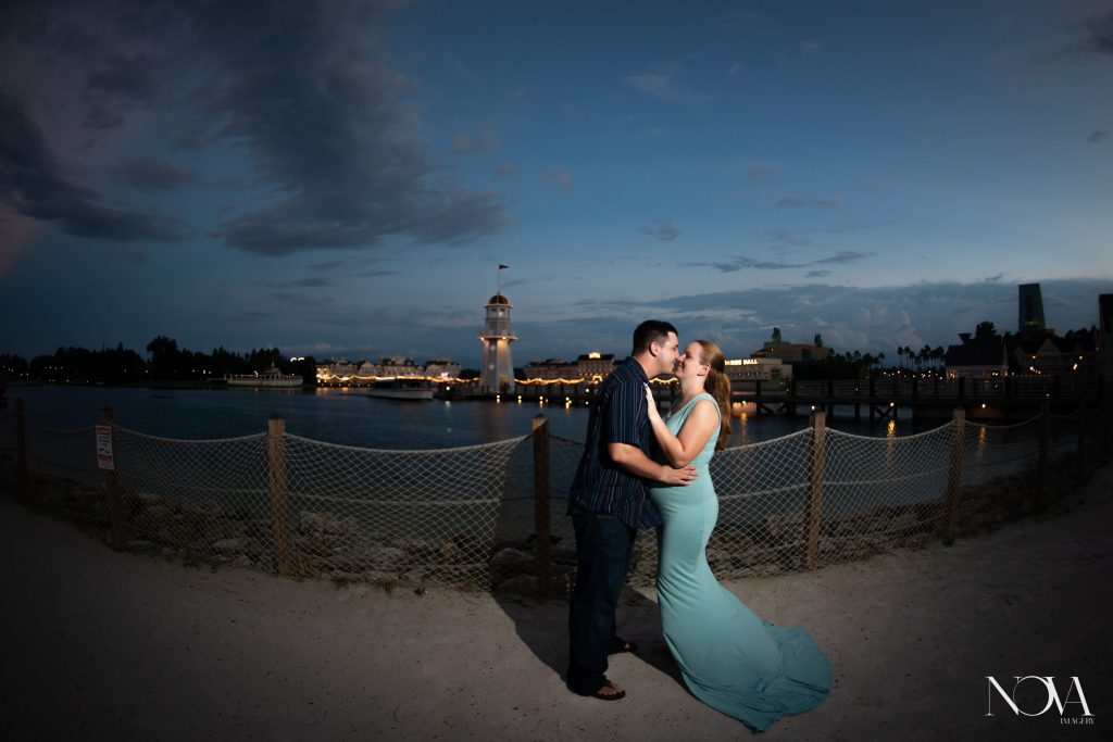 Soon to be parents kissing at Disney’s Beach Club Resort, with lighthouse in the background.