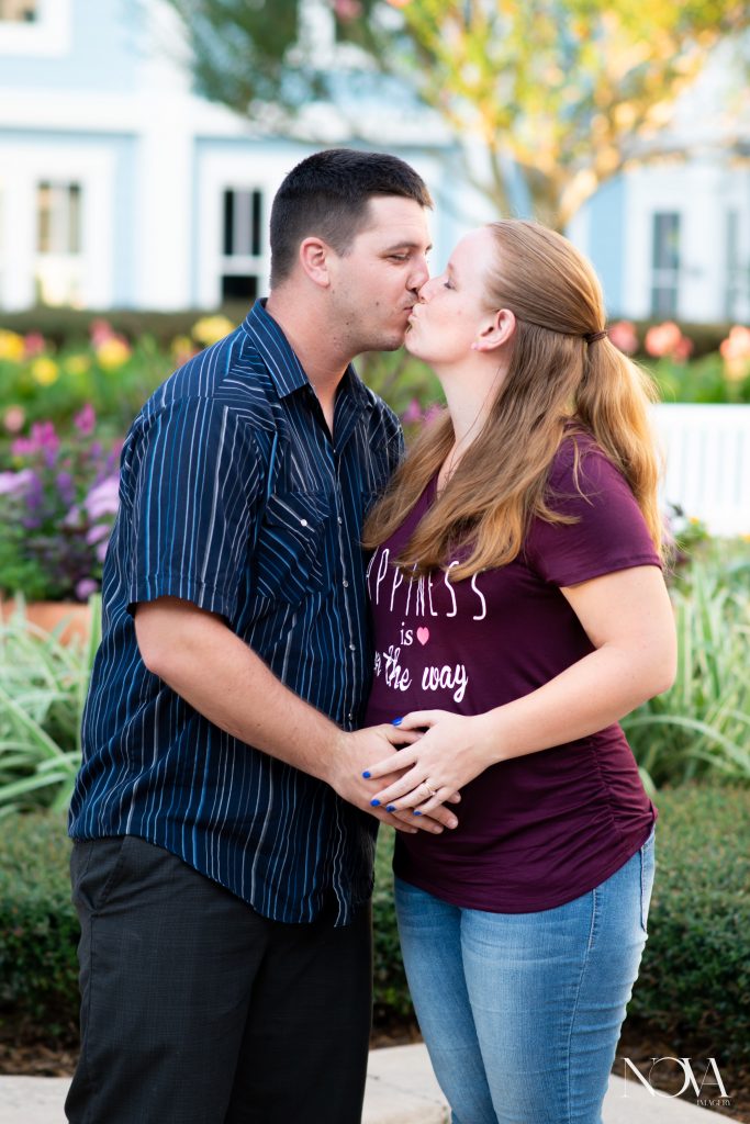 Soon to be parents kissing in front of flower bed at Disney's Beach Club Resort.