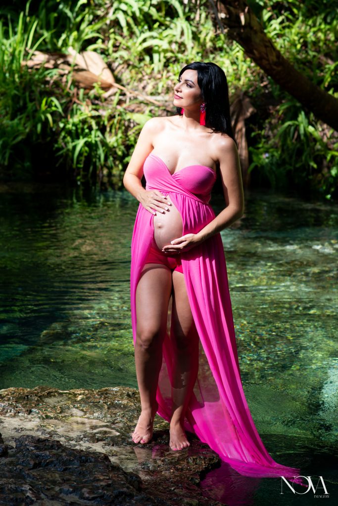 Pregnant mom posing by the water in a pink dress, at Kelly Park.