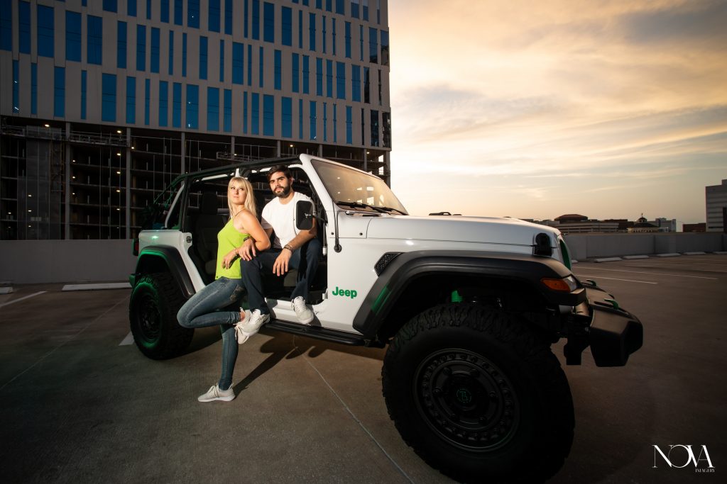 Engaged couple sitting in a Jeep on a rooftop venue