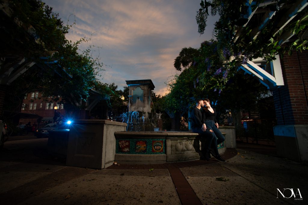 Engaged couple kissing on a water fountain in downtown Orlando for a photo.