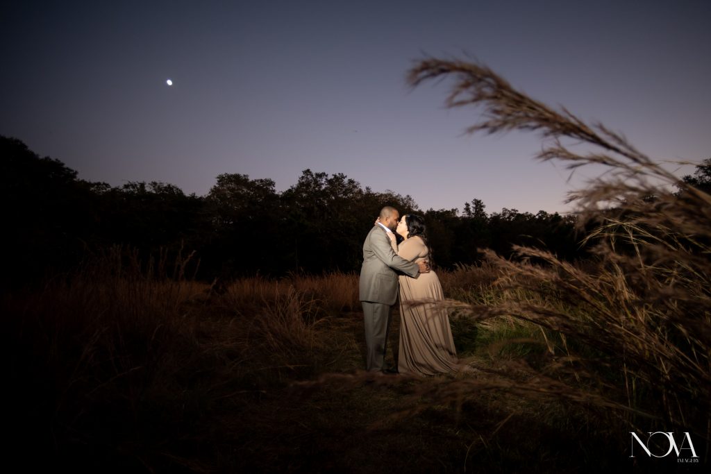 Couple kissing while in tall dry grass during their engagement photo session at Lake Runnymede.
