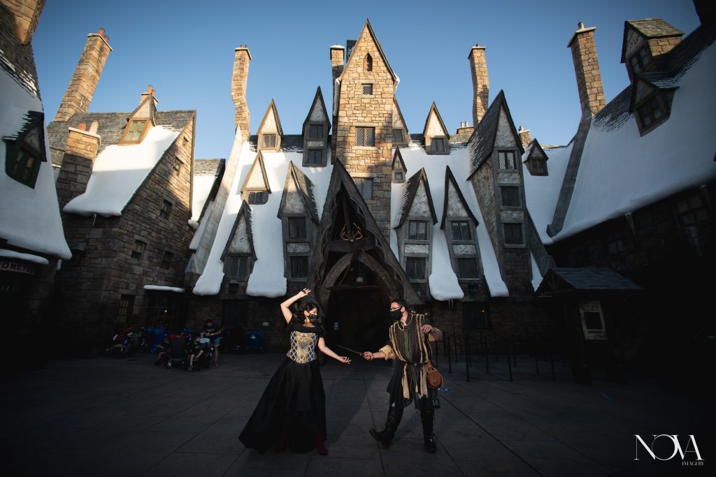 Couple posing with wands for their sunset engagement session at Hogwarts.