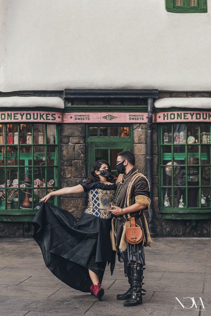 Couple taking engagement photos in front of Honeydukes at Island of Adventure.