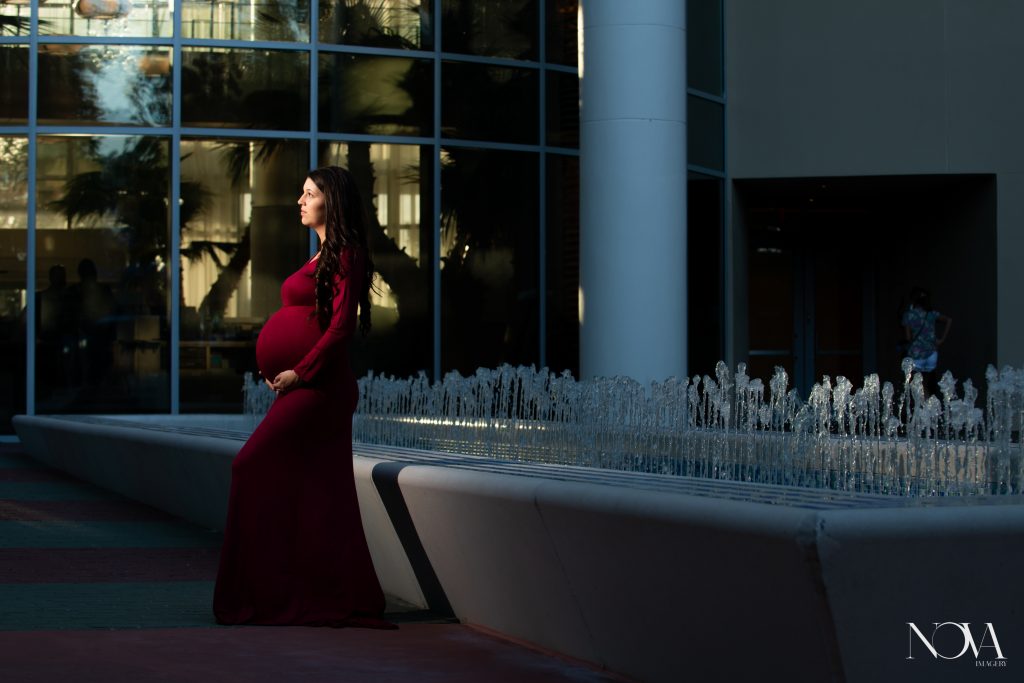 Mommy to be looking off to the side by a water fountain during her Disney’s Contemporary maternity session.