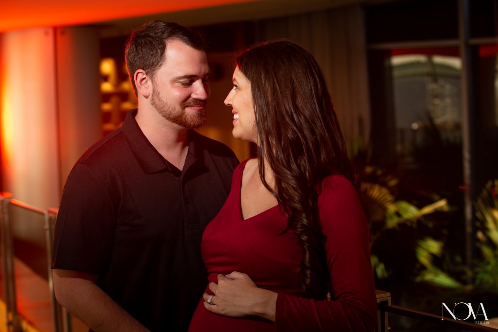 Parents to be smiling at each other during their maternity session inside Disney’s Bay Lake Tower.
