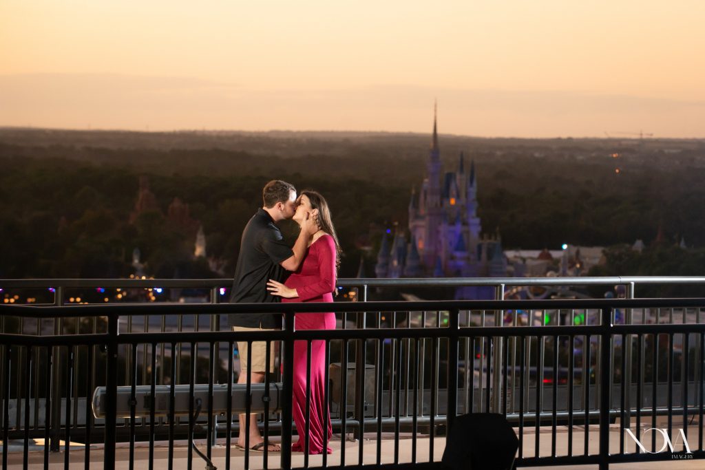 Couple kissing during sunset on the catwalk for their maternity session at Disney’s Contemporary.