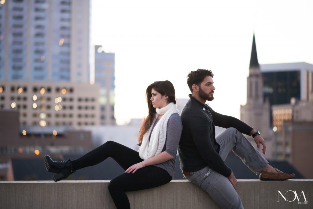 Couple sitting on rooftop in Downtown Orlando for engagement photo session