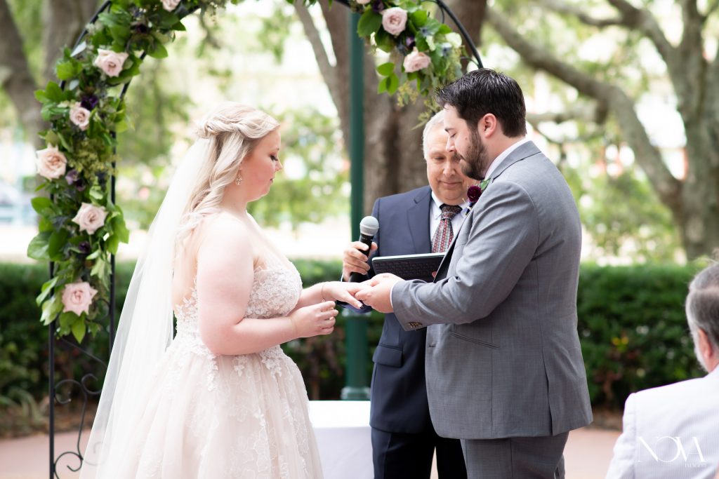 Groom placing ring on bride’s finger during wedding ceremony at Swan and Dolphin.