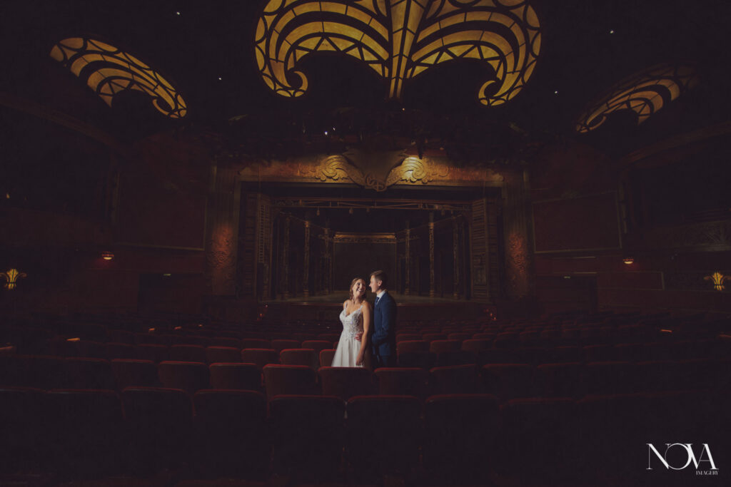 Bride and groom captured by photographer inside the Walt Disney Theater for their DCL wedding photography.